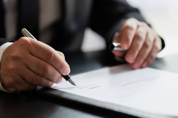 Man signing a piece of paper with a pen.